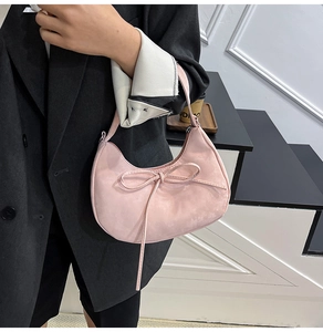 Detail of pink crescent bag featuring a long tassel bow and soft matte texture