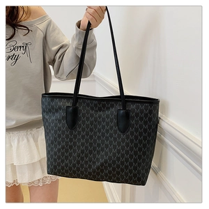 Model holding a large black tote bag with grey M letter print and sturdy dual handles