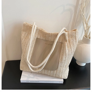 Detail of hand-woven straw tote bag with leather logo patch and cotton rope handles