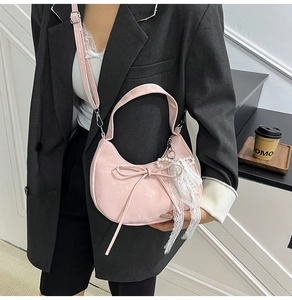 Detailed shot of pink leather handbag featuring a delicate bow and white lace pearl charm