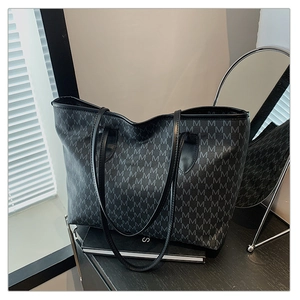 Close-up of printed monogram tote bag with sturdy leather straps on a dark desk