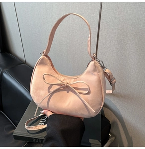 Detail view of pink crescent bag with bow decoration and adjustable shoulder strap