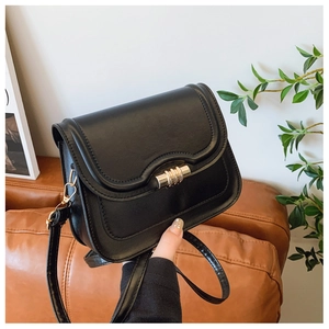 Close-up of black crossbody bag featuring a scalloped flap and gold rotating metal lock