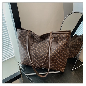 Detail of the brown monogram print on a large capacity tote bag with long shoulder straps