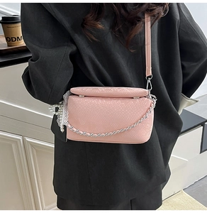 Detail view of pink snakeskin leather bag with silver chain and pearl lace charm