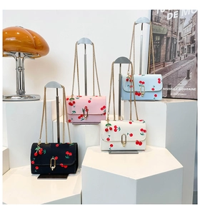 Detail of cherry print saddle bags in four colors with gold chain straps and charms