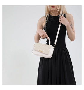 Detail of off-white crossbody bag with beige herringbone weave and gold metal accent