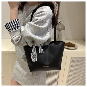Detalle de bolso tote de cuero PU negro con lazo de encaje y logotipo dorado fashion