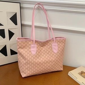 Pink printed tote bag with M patterns and long shoulder straps on a wooden table