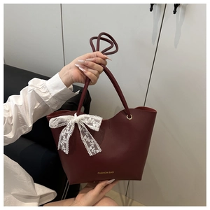 Detalle del bolso tote burdeos en cuero sintético con lazo de encaje blanco y logo