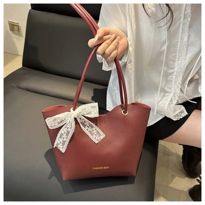 Detalle de bolso tote de cuero PU granate con lazo de encaje blanco y letras doradas