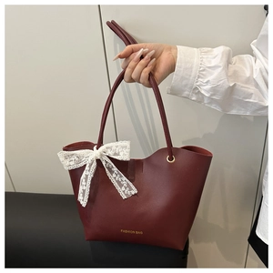 Detalle de bolso tote granate con lazo de encaje blanco y texto decorativo moderno