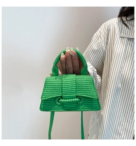 Detail of green woven texture and top handle on a fashion hourglass handbag