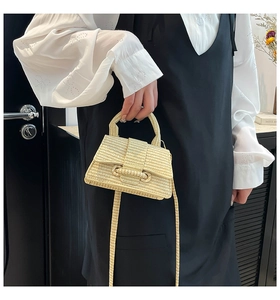 Detail of light yellow woven mini bag with fine straw texture and matching shoulder strap