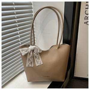 Detalle de bolso tote de cuero caqui con lazo de encaje bajo luz natural de ventana