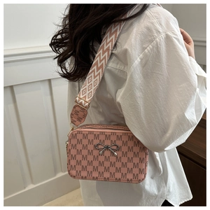 Detail of pink crossbody camera bag with M-letter print and wide pattern strap