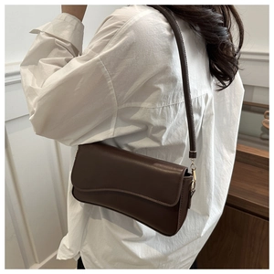 Detail view of a vintage dark brown leather shoulder bag with gold metal buckle