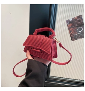 Close-up of red woven texture handbag with sleek cylindrical clasp and sturdy top handle