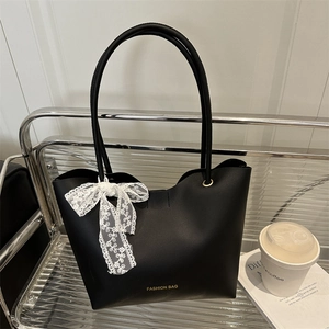 Bolso tote negro minimalista con lazo de encaje en una silla moderna