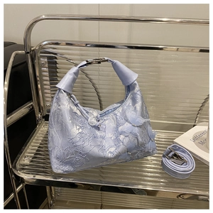 Detail view of light blue lace bucket bag with 3D butterfly embroidery and a shoulder strap
