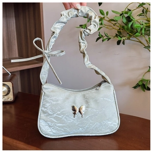 Détail du sac à bandoulière froncé vert sauge avec emblème papillon et nœud décoratif