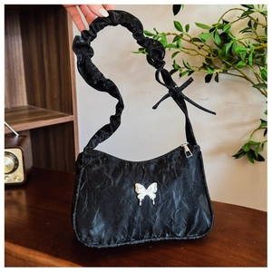 Détail du sac plissé noir avec breloque papillon argentée et anse style chouchou plissée