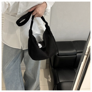 Dettaglio della borsa hobo in velluto nero con trama morbida e ciondolo a cartone animato