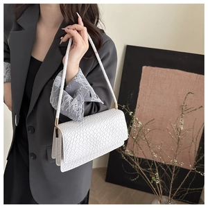 Close-up of white woven texture shoulder bag with rectangle flap and braided strap