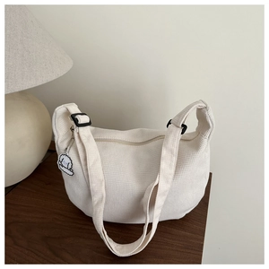 Detail of cream waffle texture shoulder bag with cute cloud pendant on wooden table