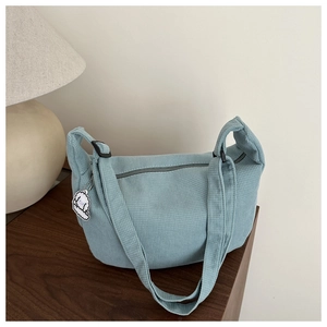 Close-up of light blue waffle-texture shoulder bag with cute puppy pendant on wood table