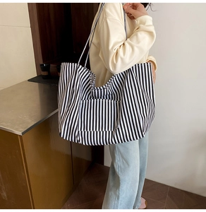 Detail shot of black and white striped canvas tote bag with front pocket and long shoulder straps