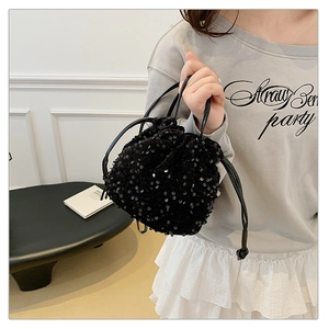 Detail of a chic black sequin drawstring bucket bag with leather-style straps