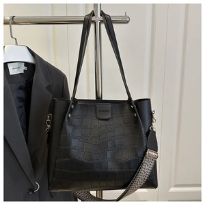 Detail of black crocodile texture tote bag with a patterned wide fabric shoulder strap