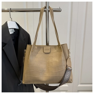 Detail of beige crocodile embossed tote bag featuring a decorative ethnic woven strap