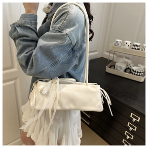 Détail du sac baguette blanc avec nœud en dentelle et cordon sur l'épaule du mannequin