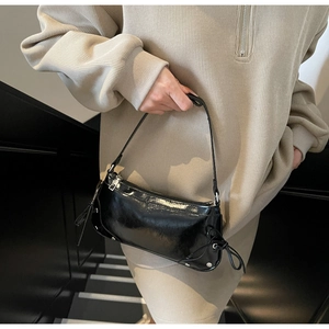 Λεπτομέρεια μαύρης γυαλιστερής δερμάτινης τσάντας με μεταλλικά τρουκ και πλαϊνό κορδόνι