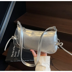 Detail of silver faux leather shoulder bag with side bow decor and metallic studs