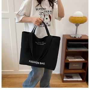 Detail shot of the black canvas tote bag showing fashion print and durable handle