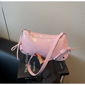 Detail of pink glossy patent leather shoulder bag with bow ties and silver metal rivets