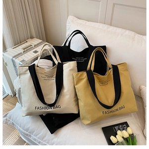 Three canvas tote bags in white, yellow, and black on a sofa with cozy home decor