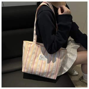 Close-up of colorful striped canvas tote bag featuring fashion label and cute bear detail