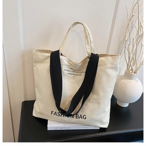 Close-up of minimalist canvas tote bag with black strap handles on a modern desk