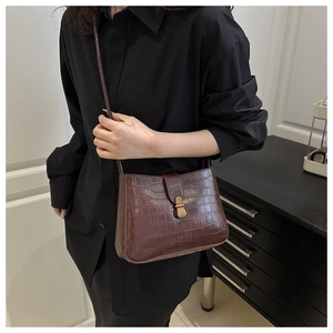 Detail of dark brown crocodile pattern shoulder bag with vintage gold metal clasp