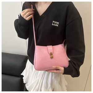 Detail of pink crocodile embossed leather bag with retro gold clasp on shoulder