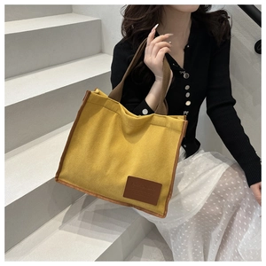 Detail of yellow waffle texture canvas tote bag with brown woven handles and leather patch