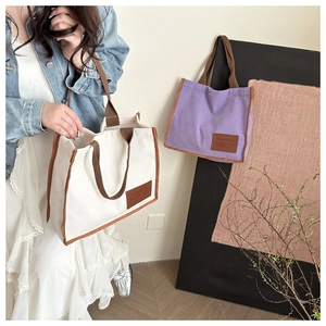 Close-up of canvas tote bag showing the reinforced brown strap and leather fashion label