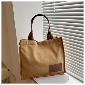 Detailed close-up of mustard yellow corduroy tote bag with brown leather fashion label