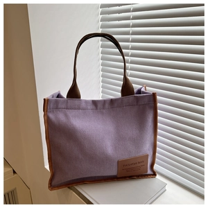 Detail of purple corduroy tote bag with brown straps and leather fashion label
