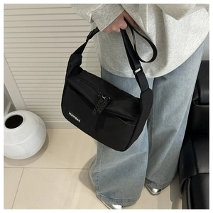 Detail of fashion black nylon crossbody bag with adjustable strap and braided zipper puller