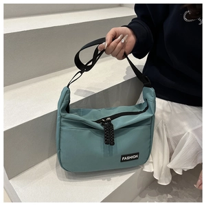 Close-up of light blue nylon crossbody bag on stone steps showing zipper and fashion label